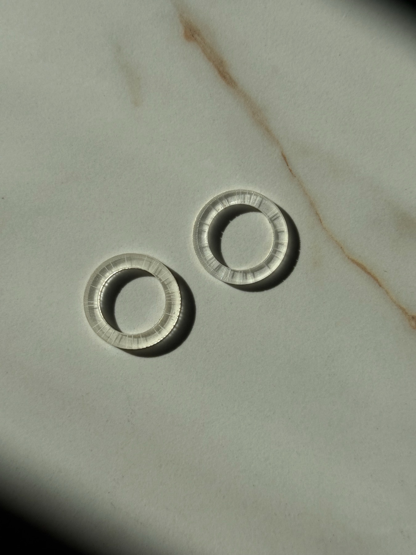 Two clear BG28 rings resting on marble in soft light