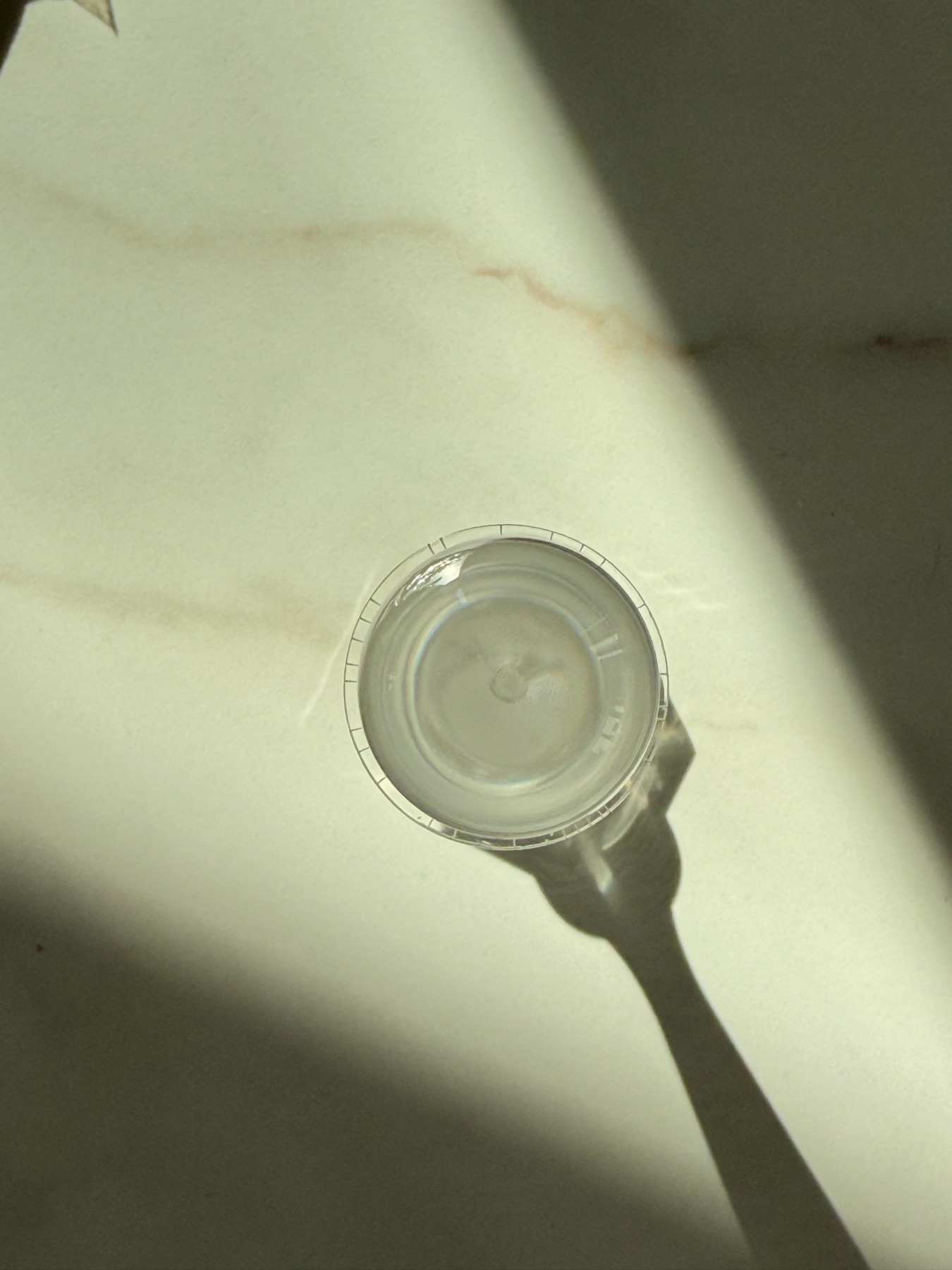 A clear disc on marble casting a long shadow in the sun