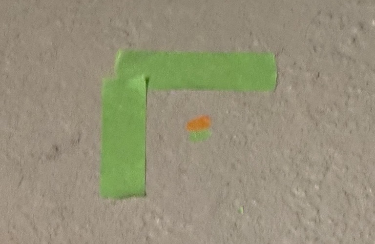 A tape corner on the floor marking a point found while exploring the space