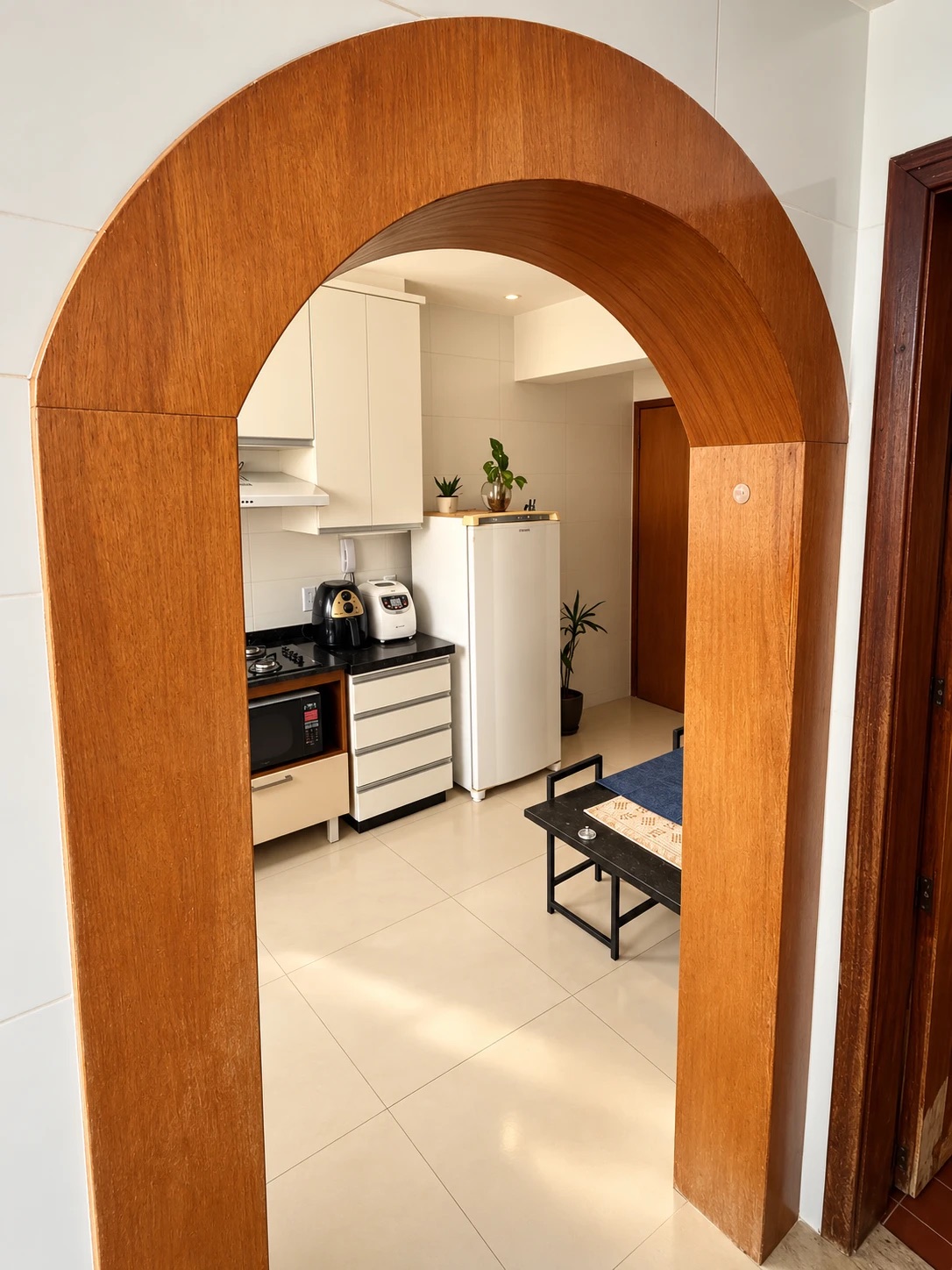 A wooden arched doorway opening onto a bright kitchen